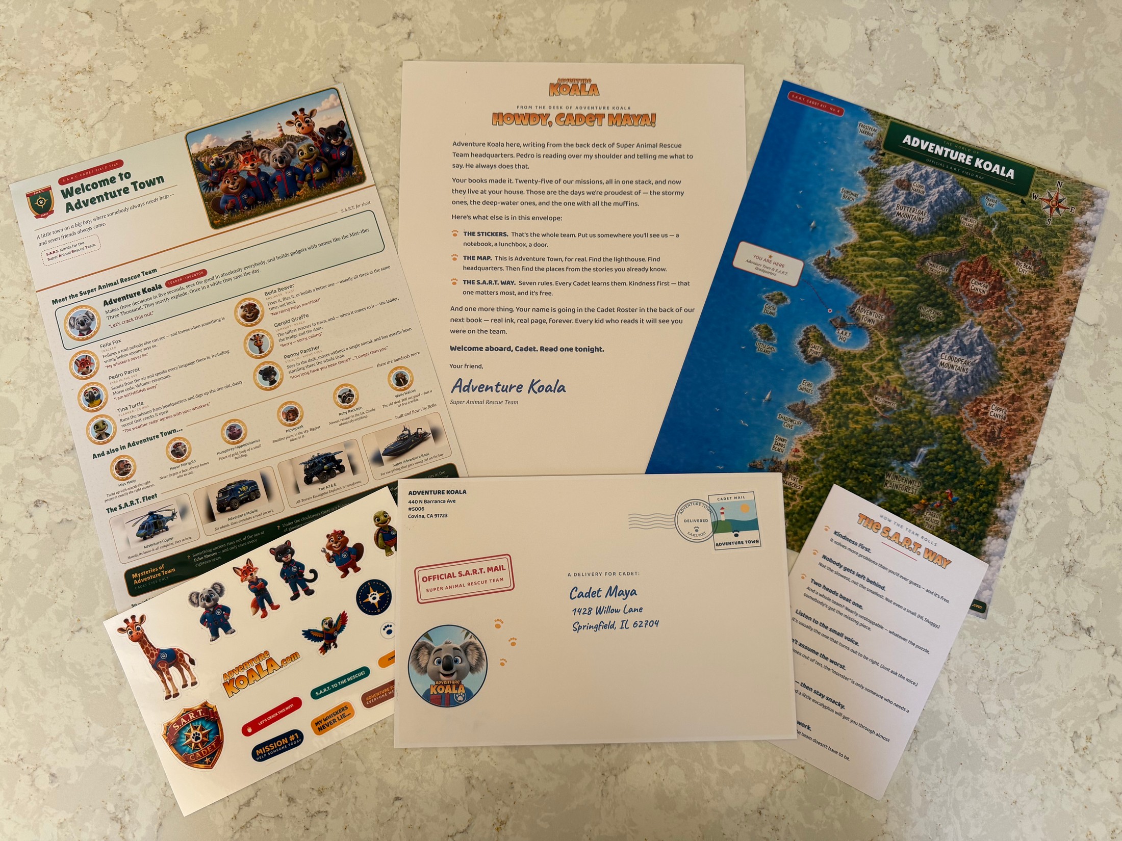 The full Adventure Koala welcome kit laid out: a personalized letter, the Cadet Field File, the Adventure Town field map, the full-team sticker sheet, the stamped envelope, and The S.A.R.T. Way card